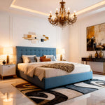 Luxurious bedroom with a blue upholstered bed, chandelier, and decorative rug.